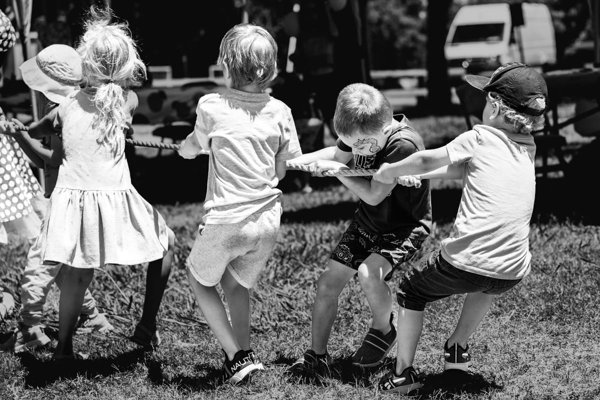 Photo of children, from the back, tugging a rope