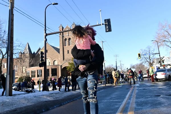 Photo of a child being carried down a street away from ICE and observers, a church in the background